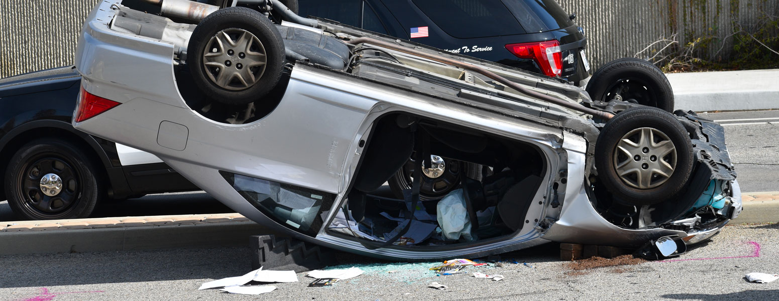 Auto accident with damaged car flipped over onto the roof with airbag deployed