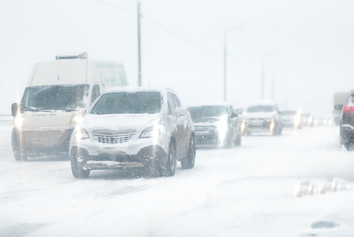 Vehicles driving on a highway in the snow. Reduce speeds in snowy weather.