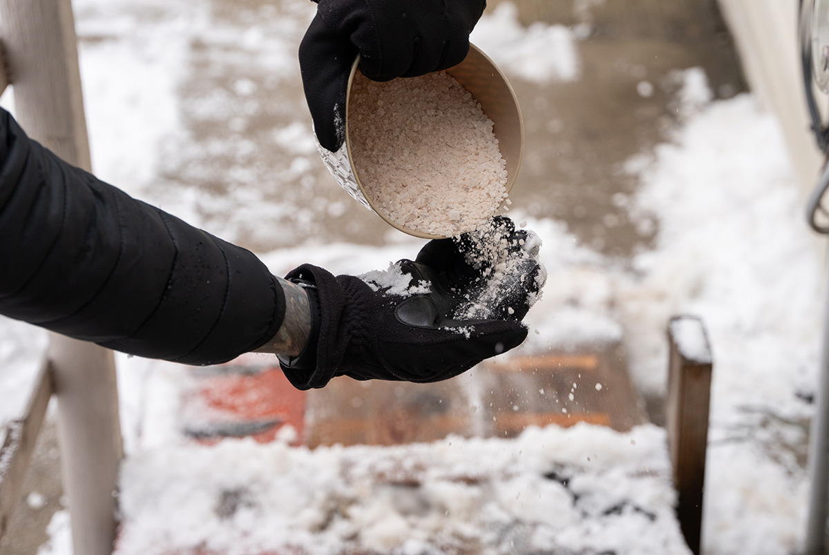Salting sidewalk outside business as part of the slip, trip, and fall indoor safety precautions.